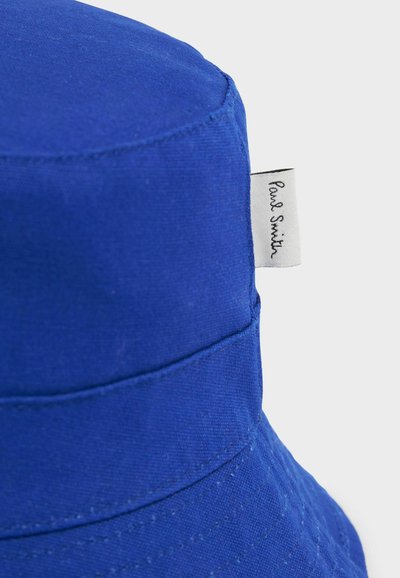 Cappello a secchiello blu in cotone, con corona strutturata e larga visiera, con una cucitura e un piccolo etichetta bianca del marchio sul lato.