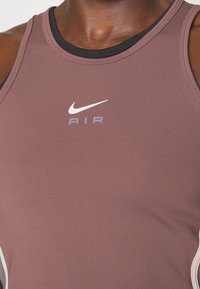 Débardeur de sport Nike AIR mauve, conçu en tissu extensible, avec des bordures noires et un logo blanc et lilas clair sur la poitrine.
