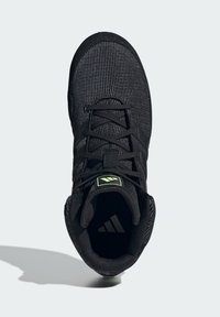 Black athletic shoe with a textured mesh upper, black laces, and green logo accent. Features a rounded toe and padded collar for comfort.