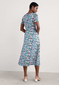 Robe midi à motifs floraux en tissu léger, avec des manches courtes, un dos en clé et une jupe évasée aux couleurs vives.