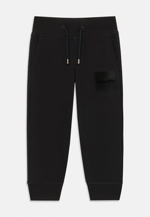 Black sweatpants made from soft fabric, featuring an elastic waistband, drawstring, and a black logo patch on the left thigh.
