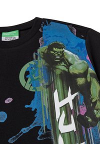 Black cotton t-shirt featuring a colorful graphic design of the Hulk and an Avengers logo in green, with splashes of blue and pink paint.