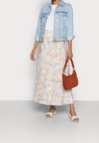 Denimjack, witte t-shirt, bloemen maxi rok in pastelkleuren, bruine suède handtas en crème blokhak sandalen.