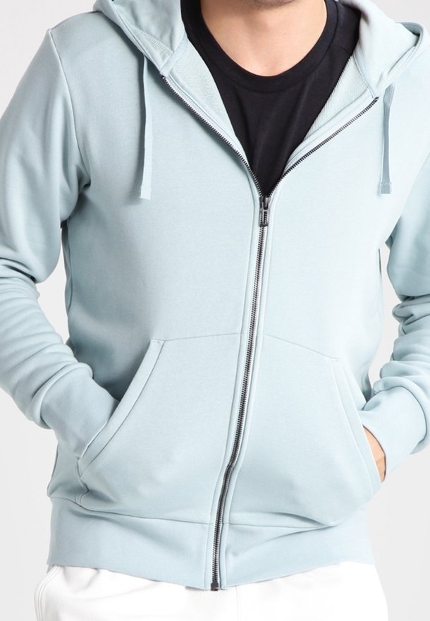 Sweat à capuche bleu clair zippé avec une poche à l'avant, des cordons de serrage sur la capuche et des détails à poignets côtelés. Texture de tissu lisse.