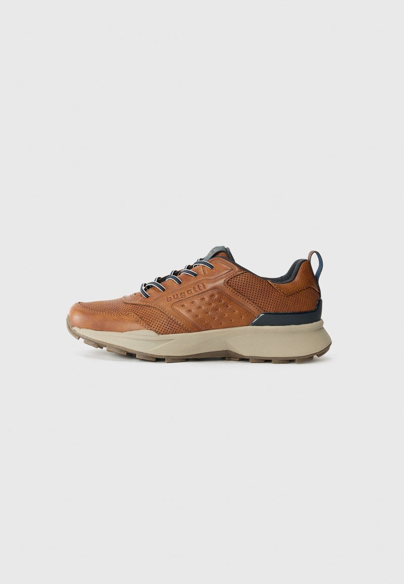 Baskets en cuir brun avec un design perforé, accents noirs et semelle grise. Comprend des lacets et une languette à l'arrière pour un enfilage facile.