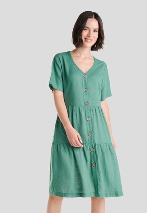 Vestido de lino verde con mangas cortas, escote en V y botones en la parte delantera. Presenta una falda en capas, botones de madera y un corte relajado.