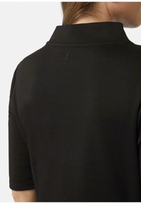 Polo noir en coton, avec un col traditionnel et des manches courtes. Détail notable : un petit logo à l'arrière.