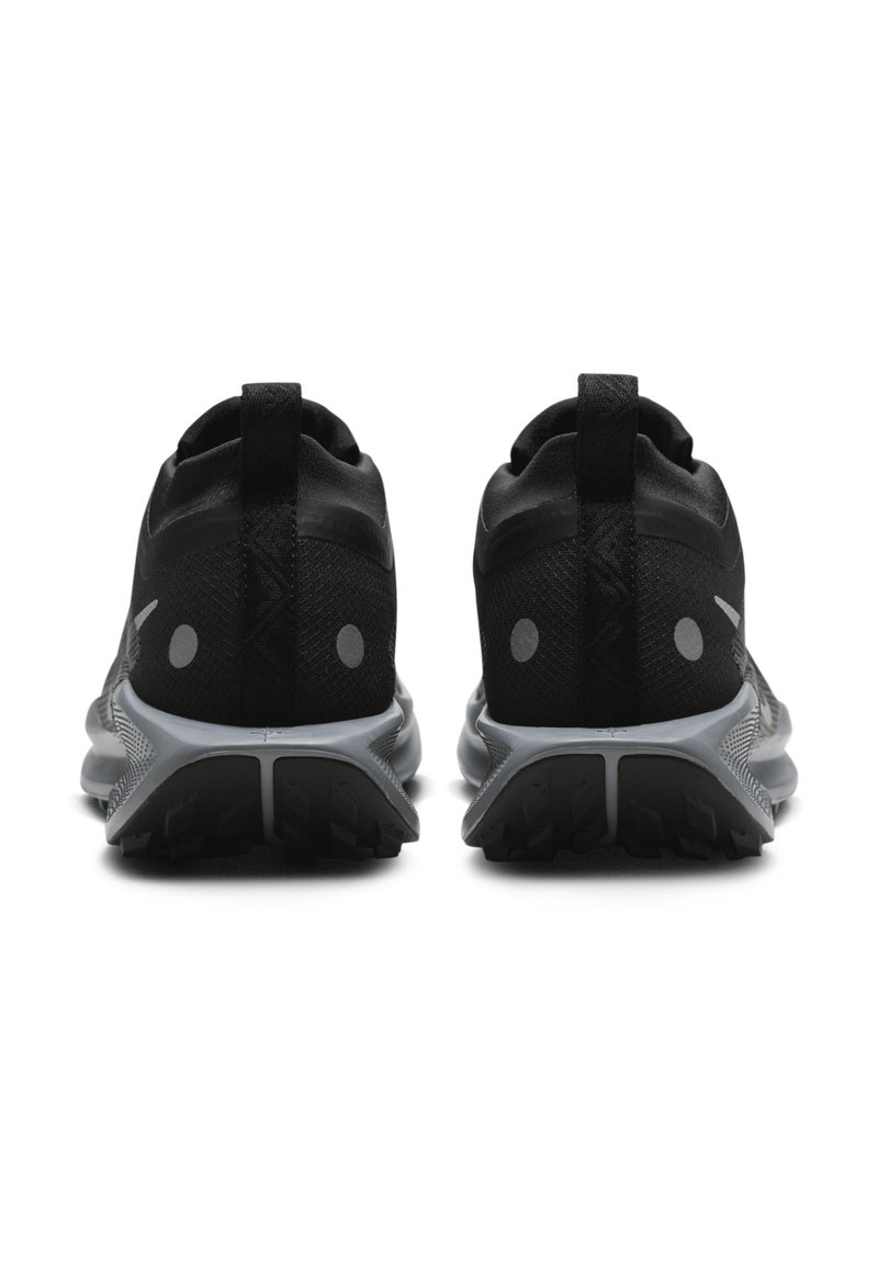 Zapatillas deportivas negras con parte superior de malla, dos puntos reflectantes para mayor visibilidad y una suela gris texturizada. Diseñadas para la comodidad y la estabilidad.