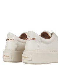 Sneakers color crema con una texture in pelle liscia, dotati di una suola spessa e leggera e di un marchio impresso in oro sul tallone.