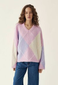 Oversized V-Ausschnitt-Pullover in Pastellfarben mit Rautenmuster in Rosa, Lila und Creme. Weicher Stoff mit gerippten Bündchen und Saum.