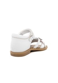 Witte leren sandalen met een gesloten hak, open teen en meerdere banden. Beschikt over een tan rubberen zool en decoratieve bloemenaccenten.