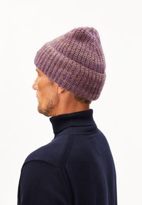 Gebreide beanie in verschillende paarse tinten, met een textuurpatroon en een slouchy, conische vorm. Gekocht met een marineblauwe coltrui.