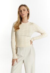 Beige dlouhý rukáv top s texturovaným pleteným vzorem a kulatým výstřihem. Přiléhavý střih, žebrované manžety a hladký povrch.