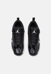 Baskets de sport noires avec une tige en cuir verni, une languette en mesh et des lacets ; logos de marque blancs ; design bas ; semelle en caoutchouc.