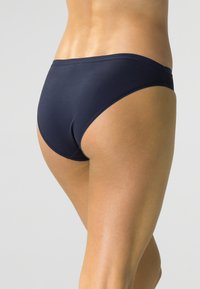 Bikini ze niebieskiego materiału o gładkiej powierzchni, z niskim stanem, elastycznym pasem i minimalistycznym designem, bez wzorów ani akcentów.