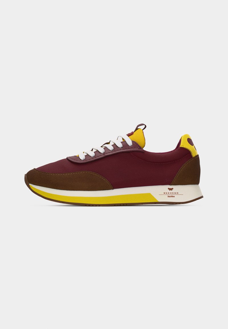 Baskets basses bordeaux et marron avec des lacets blancs, des accents jaunes et une semelle blanche et jaune sur un fond uni.