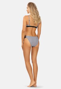 Czarny i biały bikini w kropki z cienkimi ramiączkami, z bandą z tyłu oraz dopasowanymi dolnymi częściami o niskim stanie. Gładka faktura i dopasowany krój.