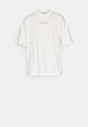 Biała, oversize'owa koszulka z krótkim rękawem i okrągłym dekoltem, z małym logo "LACOSTE" na środku przodu.