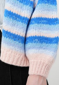 Πλεκτό πουλόβερ με οριζόντιες ρίγες σε ανοιχτό μπλε, σκούρο μπλε και απαλό ροζ χρώμα· ριμπ μανσέτες σε ροζ χρώμα· λεπτομέρεια υφής στο νήμα.