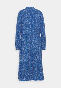 Långärmad klänning i ljusblått tyg med ett blommönster i beige. Utsådd kjol med krage och knäppning.