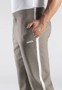 Grijze joggingbroek met een witte zijkantstreep en elastische tailleband, met een zijzak en het "Bench." logo in het wit op de voorkant.