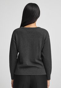 Dunkelgrauer Pullover mit legerem Schnitt, gerippten Bündchen und Saum. Hergestellt aus weichem Stoff mit glatter Oberfläche und weitem Halsauschnitt.