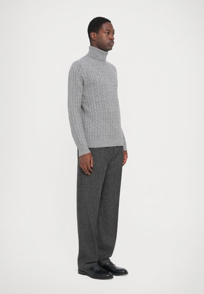 Grå kabelstrik turtleneck sweater med ribbet tekstur, parret med vide mørkegrå bukser og sorte lædersko.