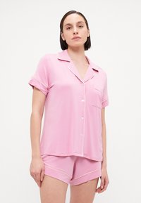Conjunto de pijama rosa de mangas curtas com uma blusa de botões com bolso e detalhes contrastantes, combinado com calções a condizer. Tecido suave.