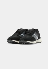 Black athletic shoes with a smooth, textured fabric upper, featuring grey stripes, lace-up closure, and a lightweight white sole.