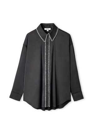 Chemise noire à manches longues avec une fermeture à boutons sur le devant, un col pointu et des coutures blanches contrastantes le long de la ligne de boutons et du col.