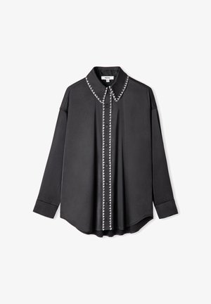 Černá dlouhá košile s knoflíkovou přední částí, ostrým límcem a kontrastním bílým prošíváním podél knoflíkové linie a límce.