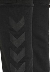 Svarta sportleggings med matt yta och strukturerad tyg, med ett reflekterande chevronmönster längs sidan för extra detalj.