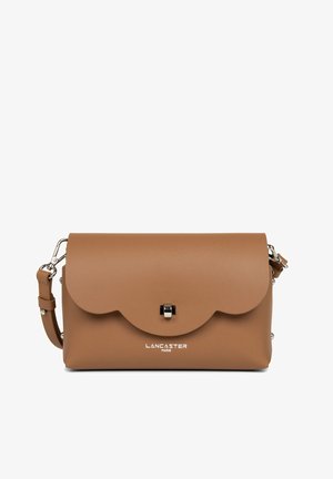 Sac à main tan avec un rabat festonné, des accessoires en argent et un logo en bas. Dispose d'une bandoulière amovible pour un port polyvalent.