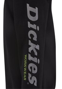 Fekete melegítőnadrág, amelyen nagy szürke színű felirat olvasható "Dickies", és kisebb zöld felirat "WORKWEAR" található a lábszáron. Keverék pamut anyagból készült.