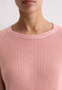 Roze gebreide trui met een ronde hals, ribbelstructuur en raglanmouwen, met een lichtgewicht en ademend ontwerp.