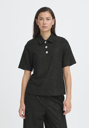 Polo nera con texture, maniche corte, caratterizzata da tre bottoni decorativi e un colletto classico. Abbinata a pantaloni neri coordinati.