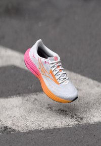 Let running sko i grå med pink og orange accenter; har en åndbar overdel, farverigt indre for og tekstureret sål.