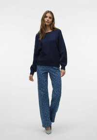 Pull navy côtelé avec des manches larges associé à un pantalon large en imprimé léopard bleu et des talons aiguilles bleu clair. Texture lisse, design décontracté.