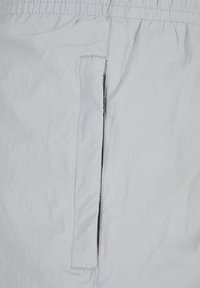 Lysegrå shorts i letvægtsstof med sidelomme, kontrastsyning og afslappet pasform. Glat tekstur med minimale designdetaljer.