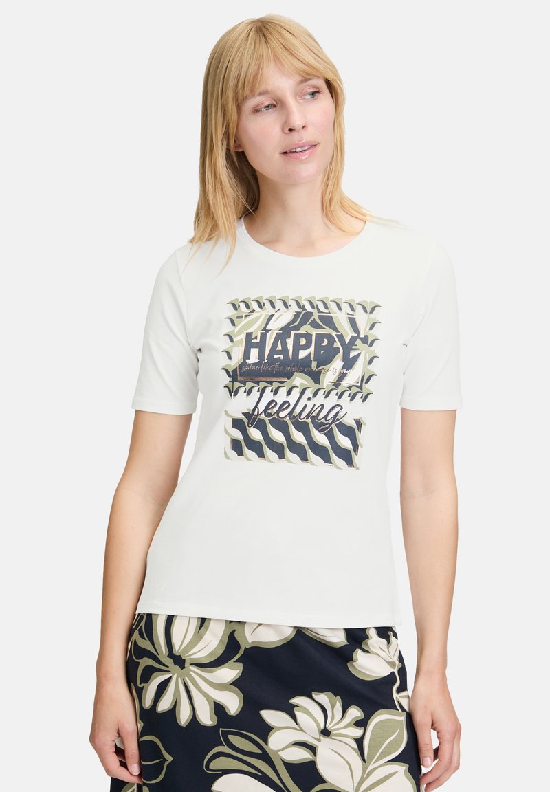 Witte katoenen T-shirt met korte mouwen, voorzien van een grafische print van de woorden "HAPPY feeling" in zwarte en groene golfpatronen.