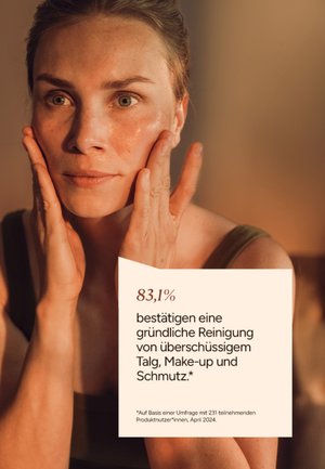 Woman gently touching her clean, glowing face with both hands, alongside German text about thorough cleansing of excess oil, makeup, and dirt.