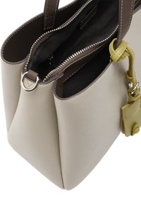 Beżowa skórzana torba na ramię z szarym wewnętrznym kieszeniem na zamek, podwójnymi uchwytami u góry oraz małym, odczepianym akcentem w oliwkowej zieleni.