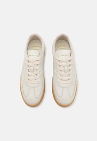 Vita lädersneakers med texturerade accenter, gummisulor och beige snören. Guld "HACKETT" logotyp på tungan och sidan.