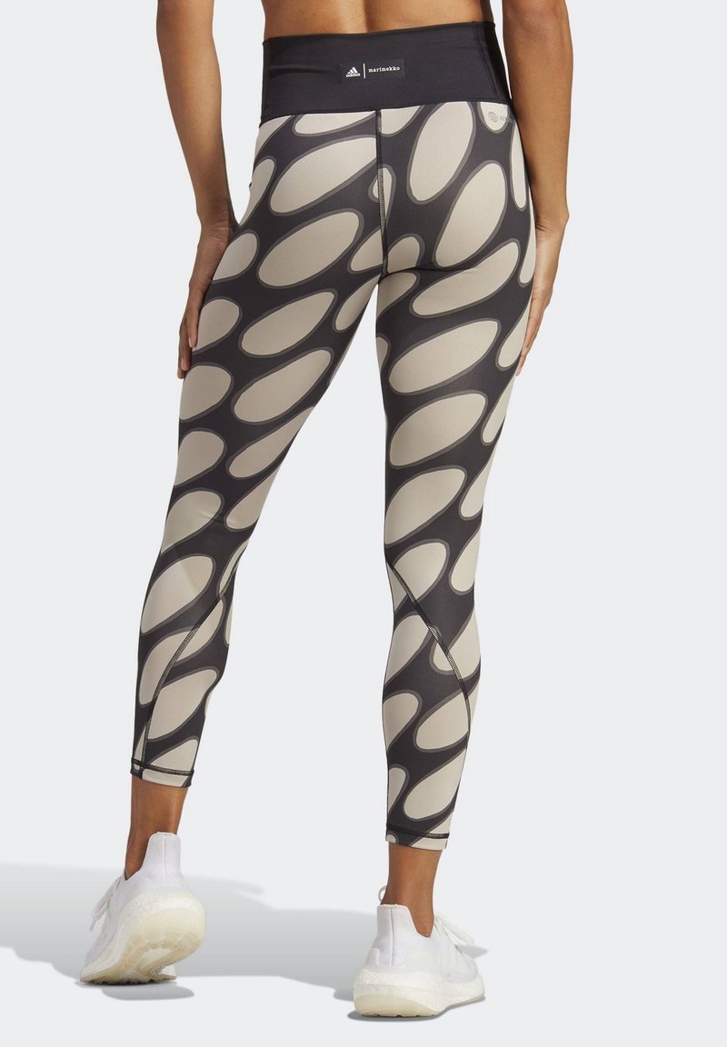Leggings negros y beige con un patrón ovalado, hechos de tela elástica. Presentan una cinturilla ancha y costuras visibles a lo largo de las piernas.