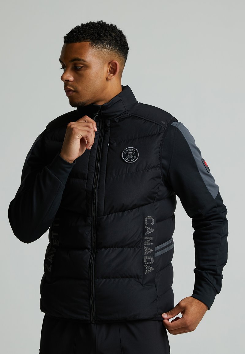 Gilet en duvet noir avec un col haut, logo sur le côté "ZAVETTI CANADA" et accents gris. Doté d'une fermeture éclair à l'avant et d'un tissu texturé.