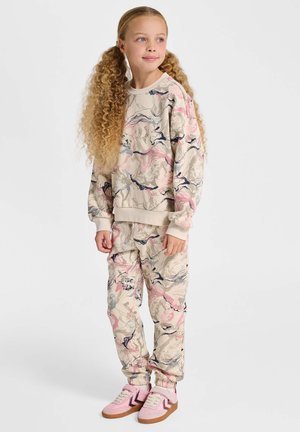 Beige sweatshirt- och sweatpants-set med ett färgstarkt abstrakt blommönster. Sweatshirten har ribbade muddar och midjeband. Rosa sneakers.
