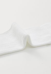 Weißer Baumwollsocken mit gerippter Textur, die eine glatte Oberfläche aufweisen, zur Hälfte gefaltet, um seine Form und Weichheit zu zeigen.