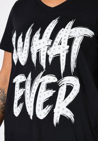 Černé bavlněné tričko s výrazným bílým nápisem "WHAT EVER" zdobené stříbrnými cvoky, s designem do V a krátkými rukávy.