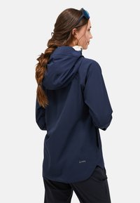 Giacca impermeabile navy con cappuccio, caratterizzata da un design elegante e un sottile logo del marchio sulla parte bassa della schiena. Texture del tessuto morbida, maniche lunghe.