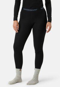 Schwarze Leggings mit strukturiertem Rippdesign und einem blau akzentuierten Bund, beschriftet mit "SWEDEMOUNT", kombiniert mit hellgrauen, gestrickten Socken.